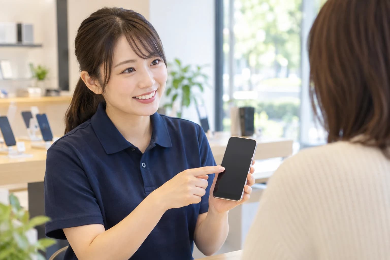 スマートフォンを説明する販売スタッフ